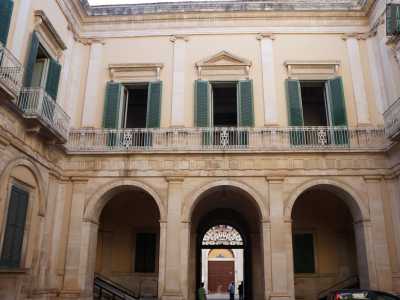 Superiamo il portale d�ingresso racchiuso tra due alte colonne e attraversiamo due semiportici con facciate ornate da lesene ritrovandoci nella corte interna quadrangolare
